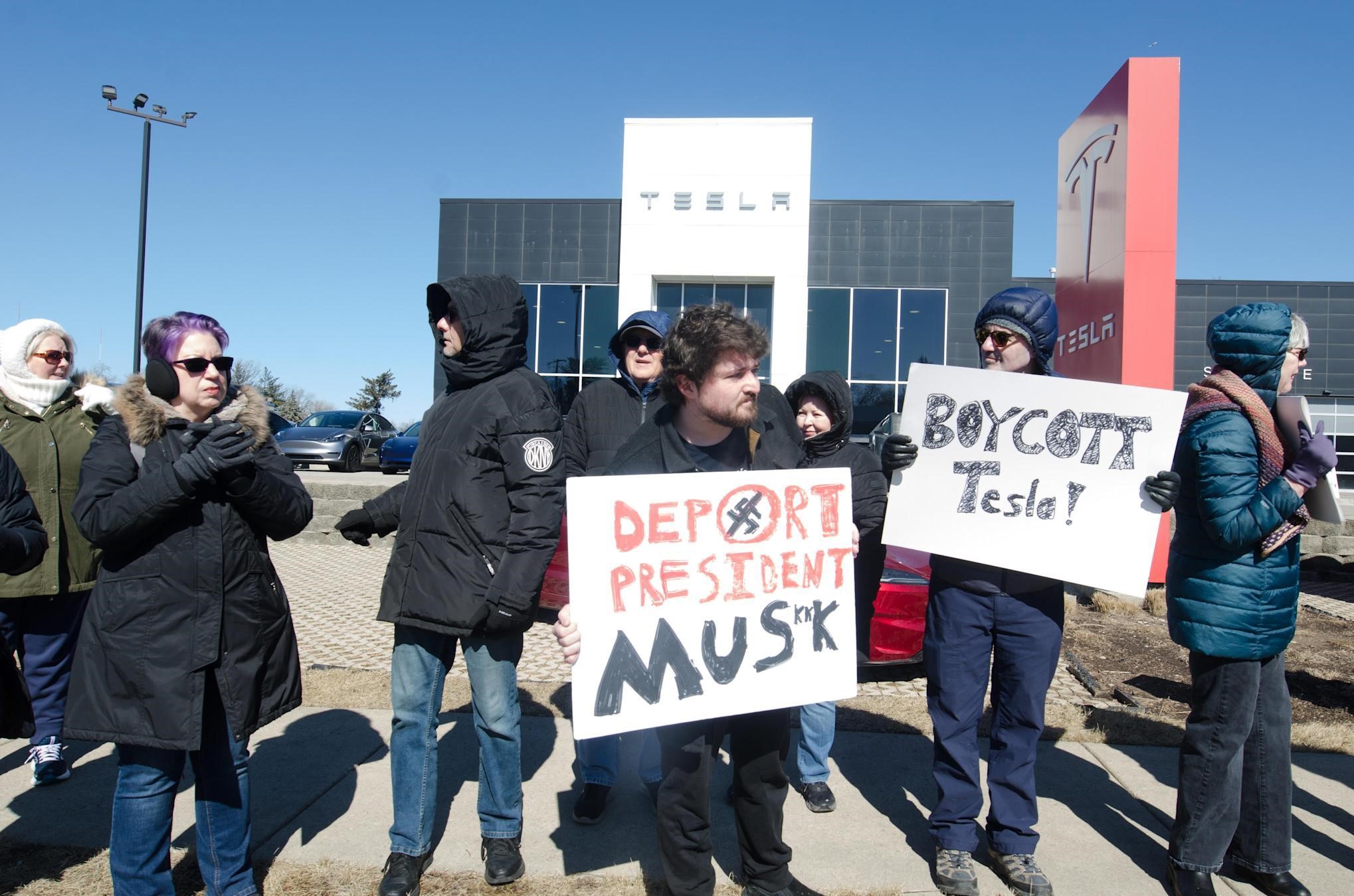 Protesters, holding banners, gather outside the Tesla showroom calling for an end to Elon Musk's 'lawless actions' and influence on the US government in Westmont, Illinois, on March 1, 2025.