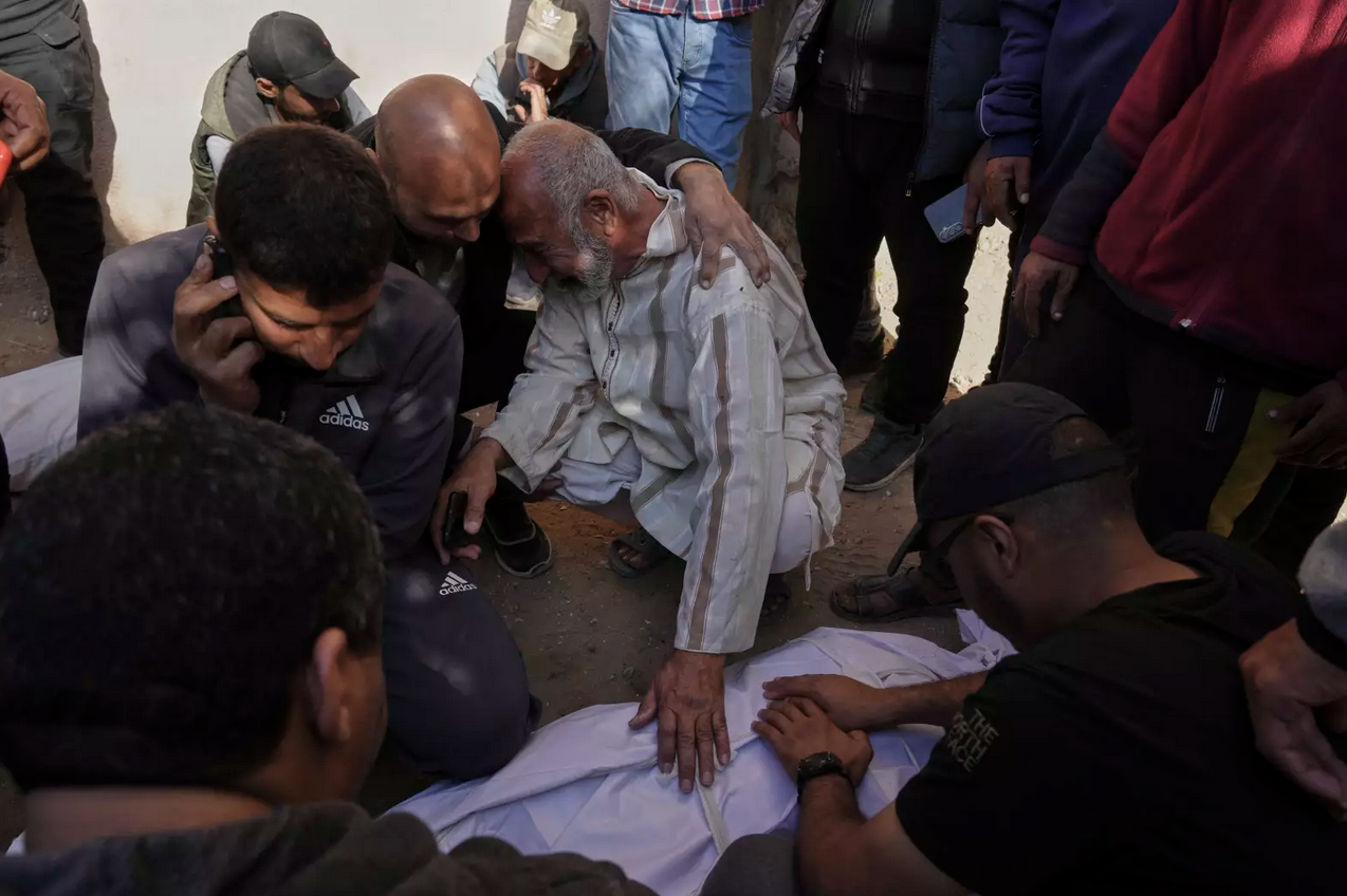 Palestinians mourn over the bodies of their relatives killed by an Israeli airstrike